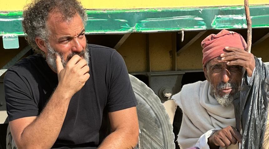 The founder in conversation with an elderly man during a field assessment