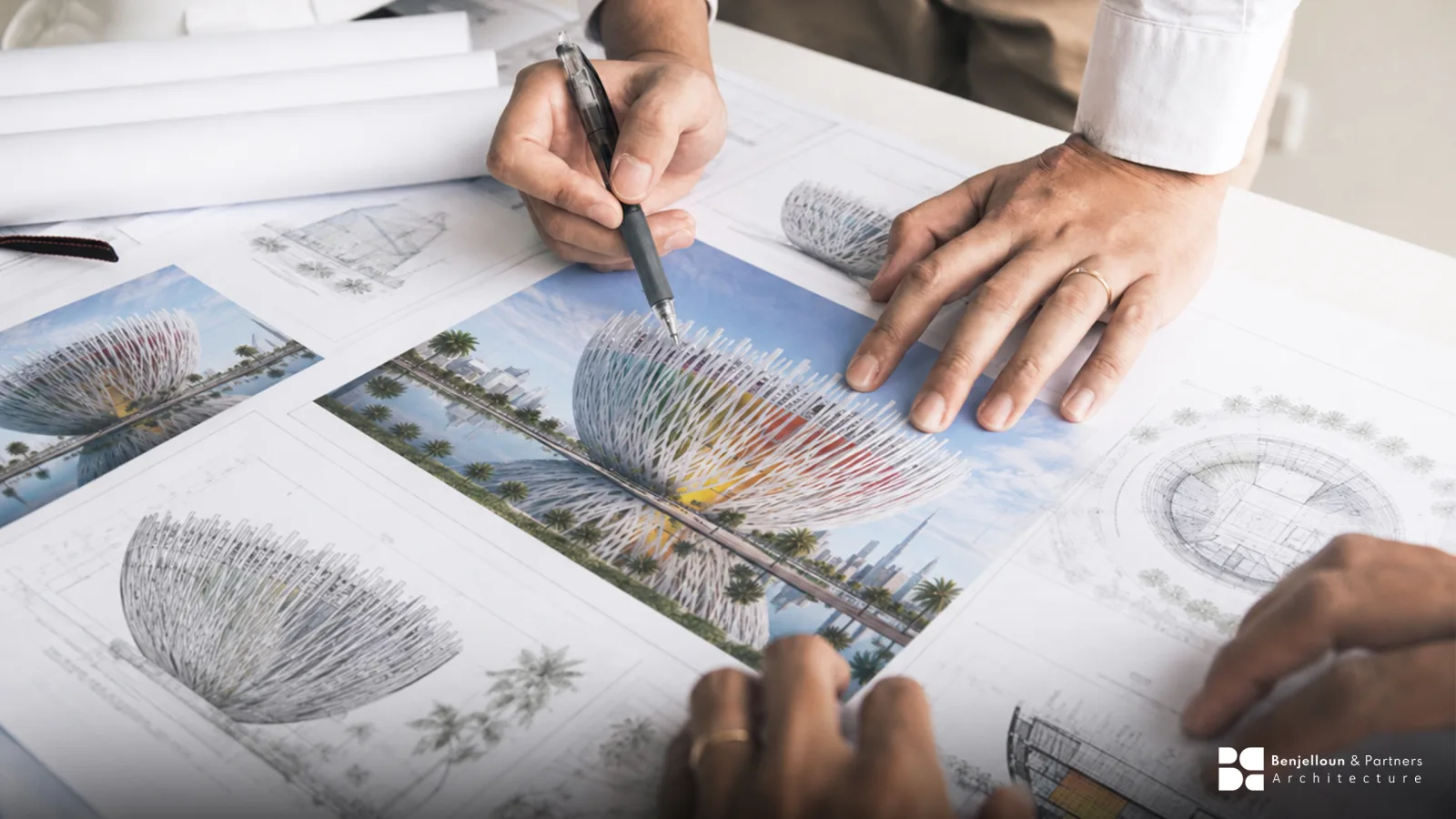 An architect's desk with drawings, a scale rule and a partly built physical model.