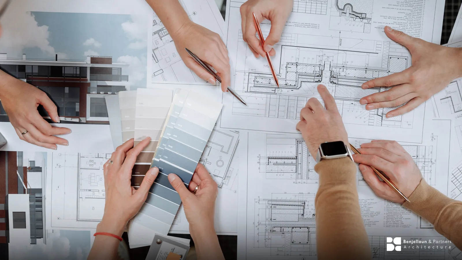 Several people working simultaneously across overlaid architectural drawings and a fan of material samples.